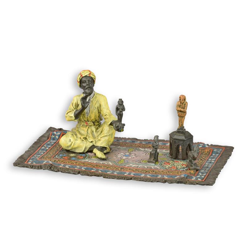 Bronzen sculptuur van oriëntaalse beeldjesverkoper op kleurrijk tapijt – klein decoratief kunstbeeld.