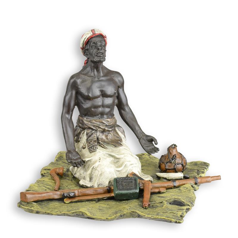 Bronzen sculptuur van een zittende wapenhandelaar met handelsattributen op gevormde basis, compact formaat